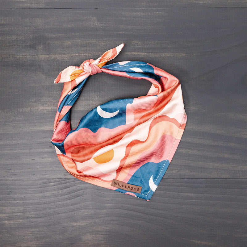 Hazy Days Bandana with abstract pink, blue, and orange design, tied on a wooden surface.