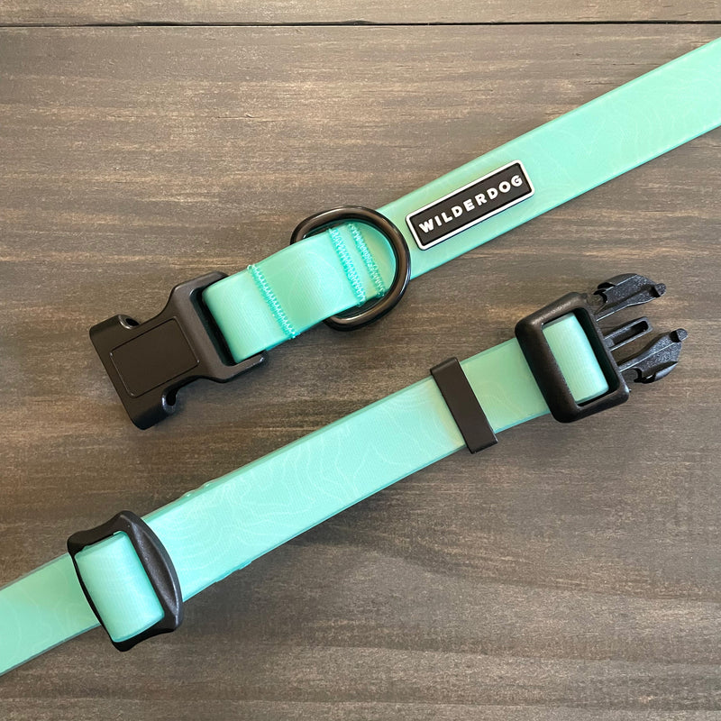 Two Seafoam Waterproof Leash + Collar Bundles, featuring adjustable straps and black plastic buckles for durability, are displayed on a wooden surface.