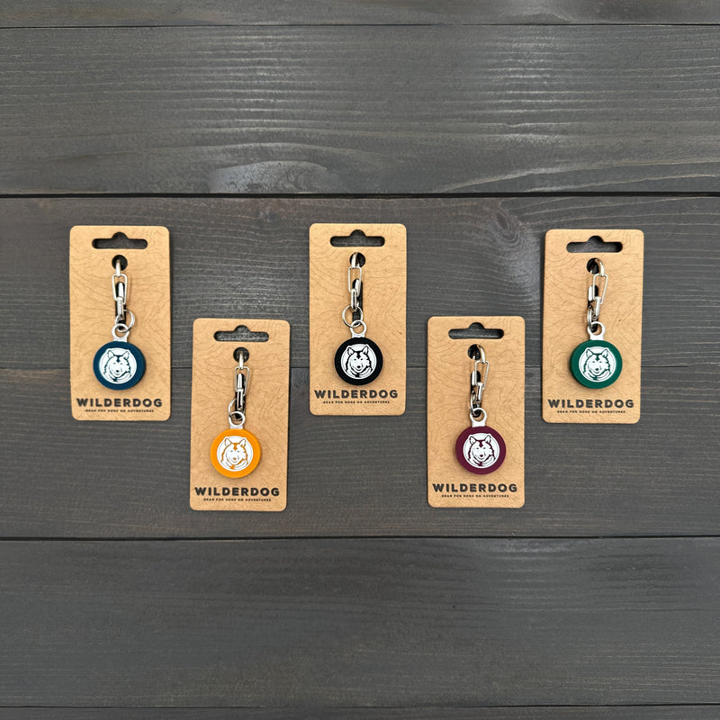 Five Smartcart21 Silicone Tags in various colors with mini carabiners on a dark wooden surface.
